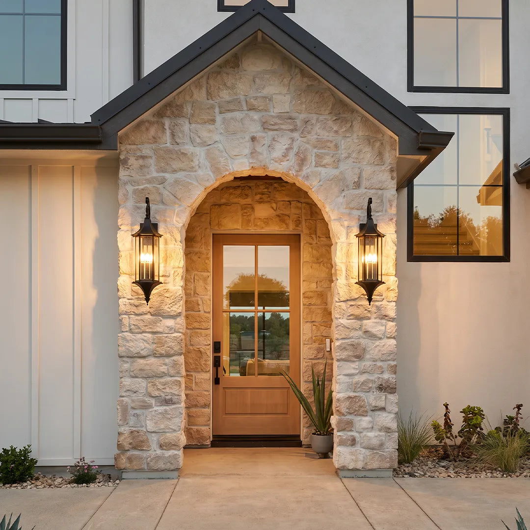 Wall lanterns outdoor lighting flanking a stone front entry with an arched doorway and matching exterior lantern fixtures.