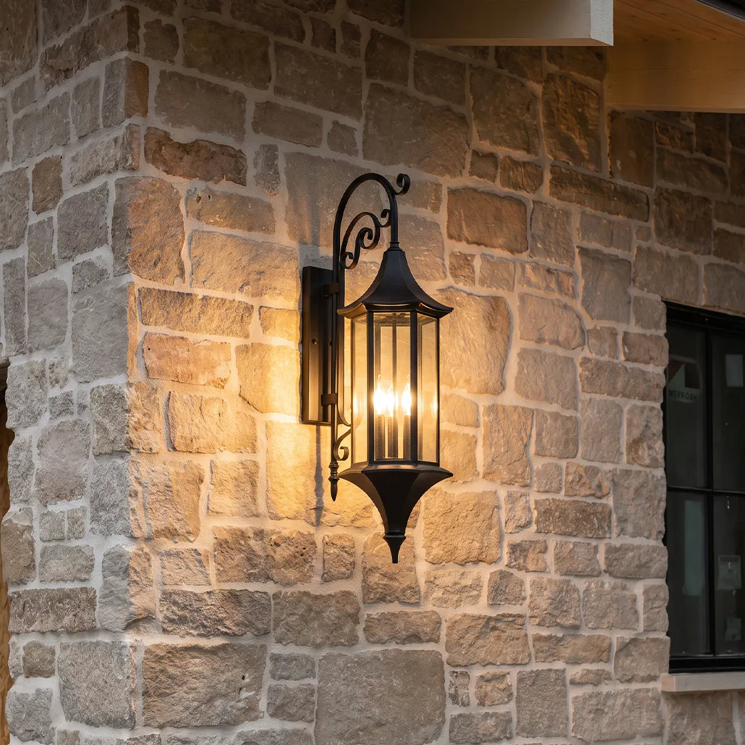 Wall lanterns outdoor lighting close-up on a stone wall showing the classic lantern silhouette and warm candle-style bulbs.