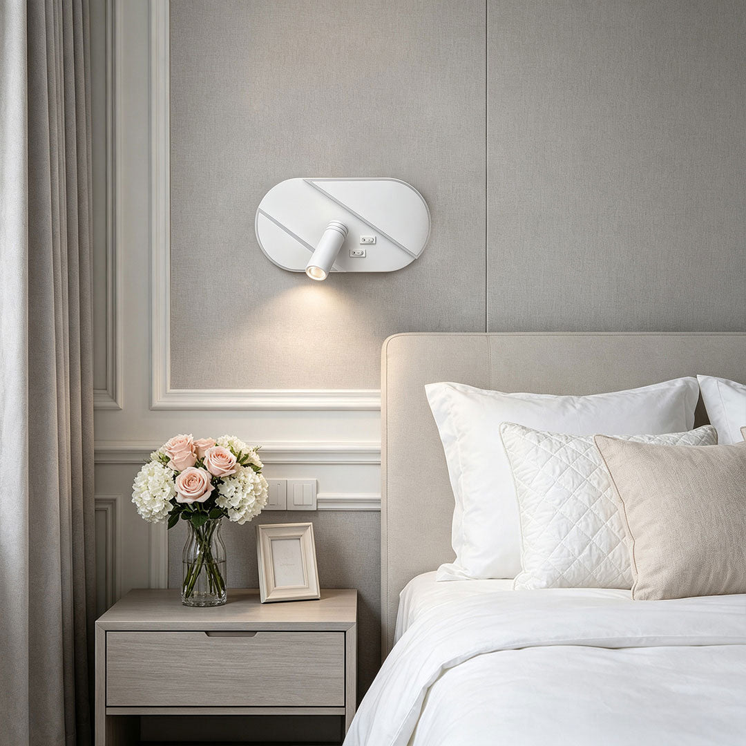 Modern wall light with reading light installed above bedside table with soft ambient bedroom illumination.
