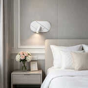 Modern wall light with reading light installed above bedside table with soft ambient bedroom illumination.