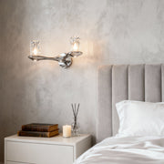 Wall lights with crystals serving as bedside lighting in serene bedroom with tufted headboard and minimal styling