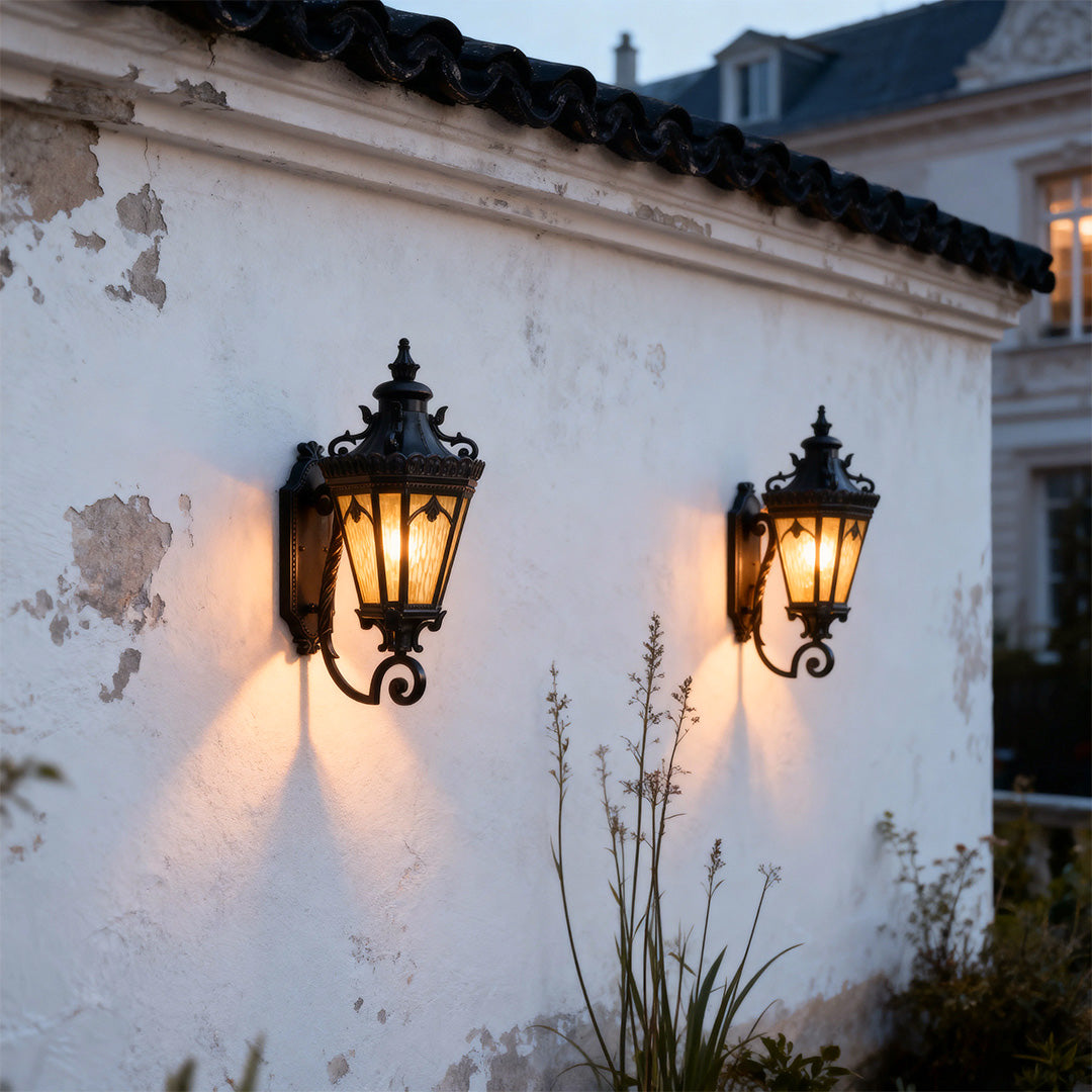 Pair of wall mount lights outdoor glowing warmly on weathered white plaster wall at dusk