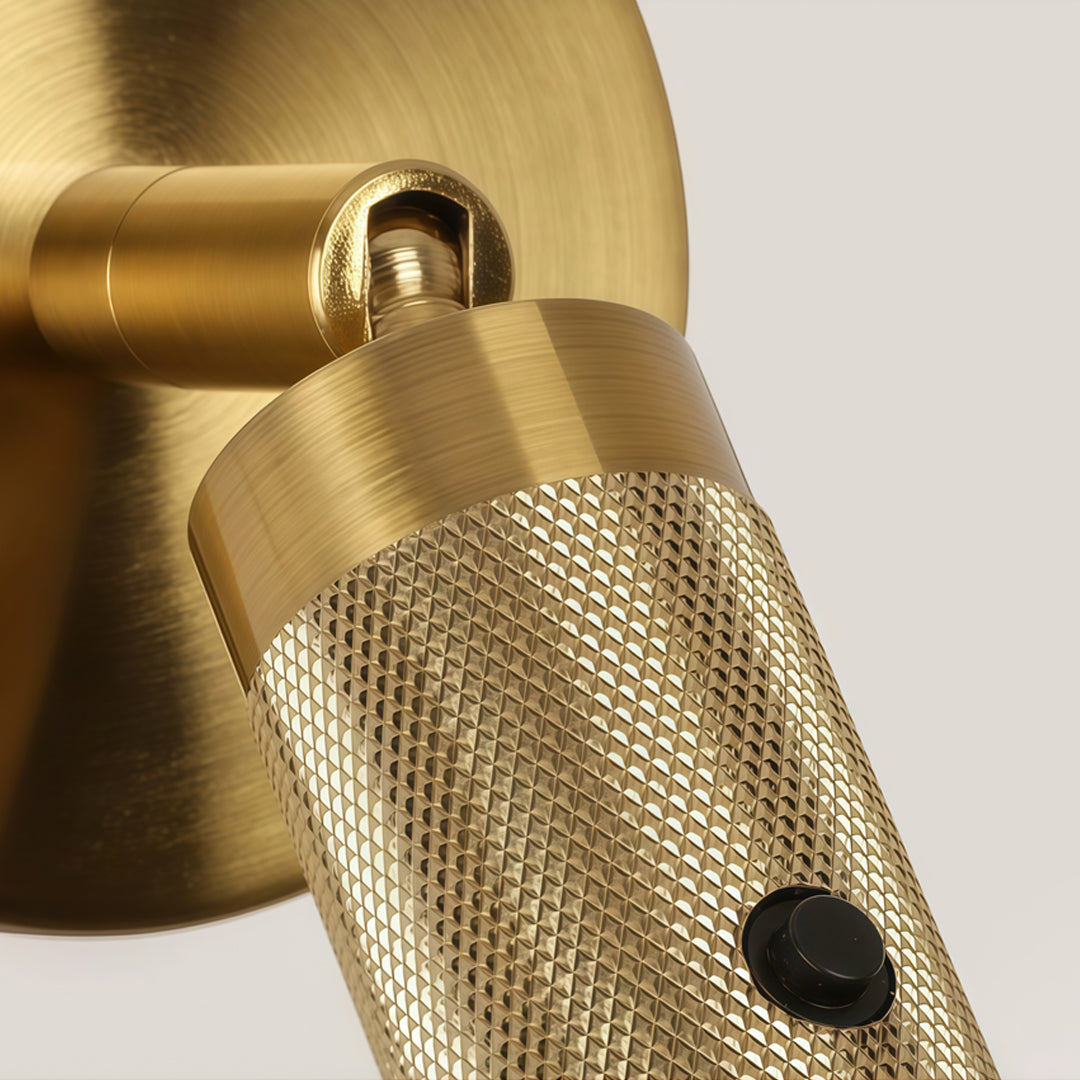 Detailed view of brass wall mount reading light featuring knurled texture and adjustable spotlight head.