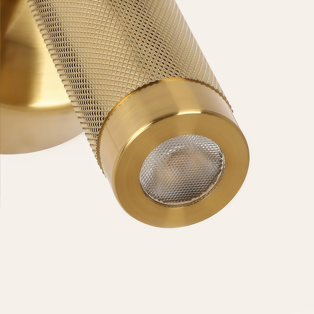 Close-up detail of gold wall mount reading light with textured cylindrical spotlight and LED lens.