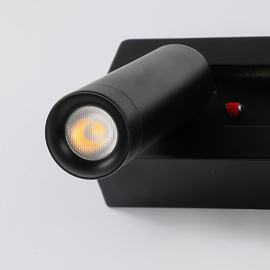 Close-up detail of black wall mount spot lights with cylindrical adjustable spotlight and LED lens.