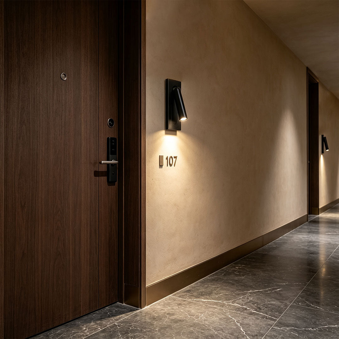Contemporary wall mount spot lights illuminating hotel hallway with sleek black adjustable spotlight fixtures.