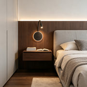 Modern wall mounted bedside light with circular LED halo and flexible reading lamp beside bed.