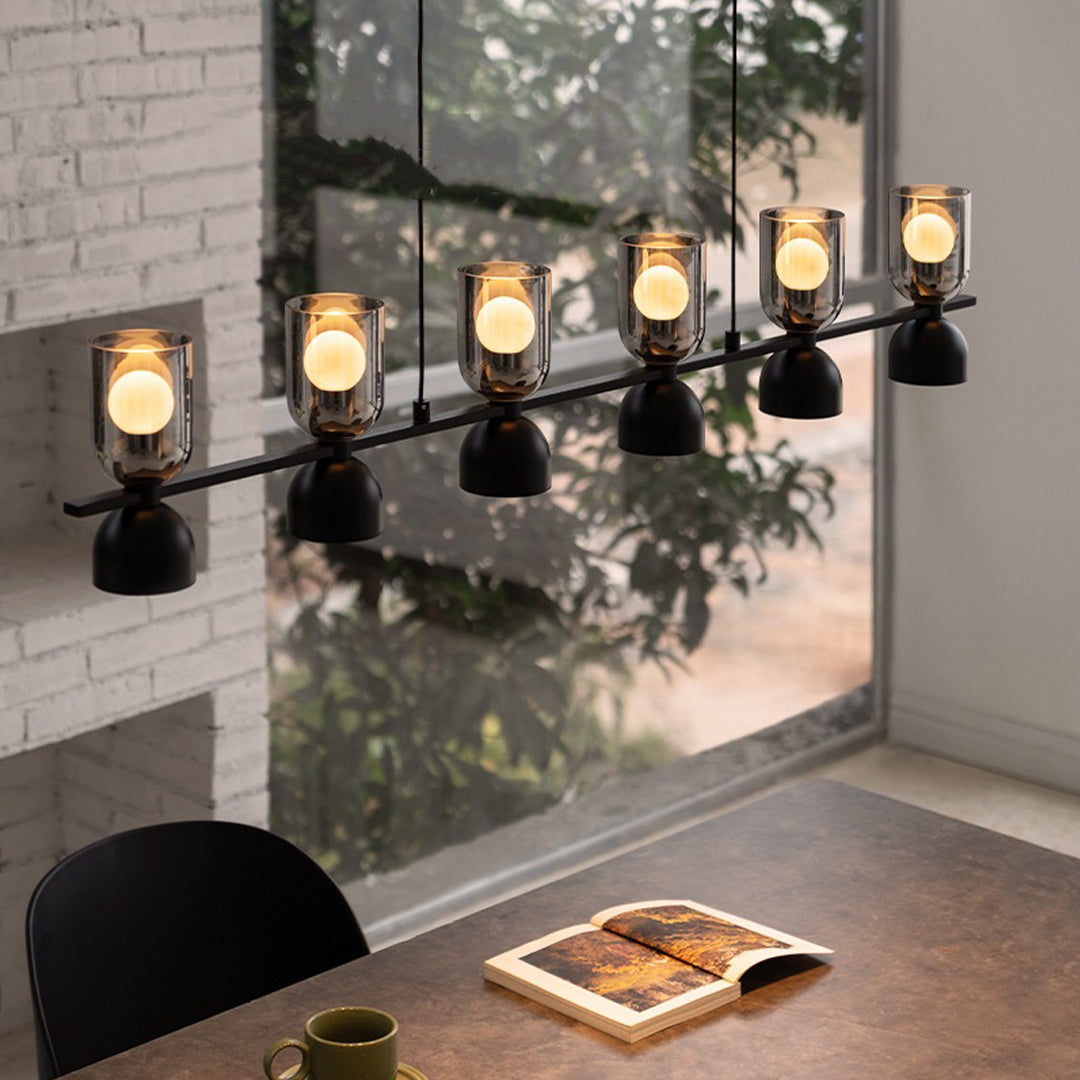 Wall-mounted linear glass pendant chandelier illuminating a cozy dining nook with industrial charm.