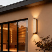 Warm-toned vertical wall-mounted linear lighting attached to a clean architectural wall at dusk.