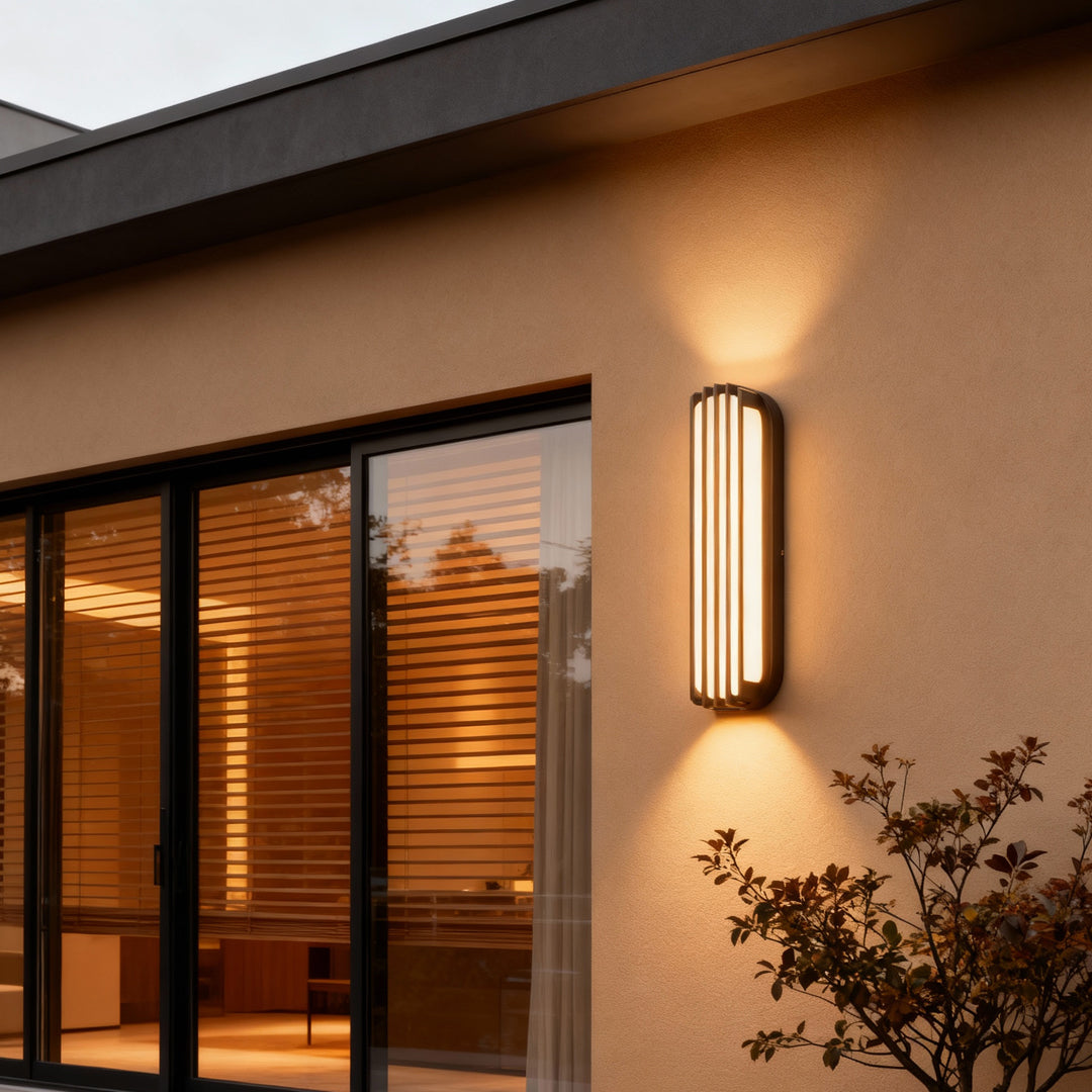 Warm-toned vertical wall-mounted linear lighting attached to a clean architectural wall at dusk.