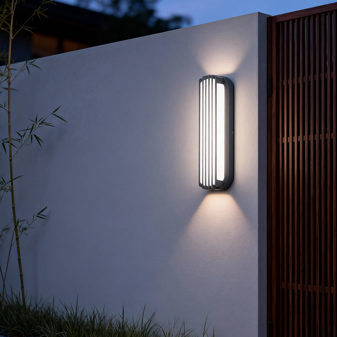 Vertical wall-mounted linear lighting illuminating a side pathway of a modern residential building.