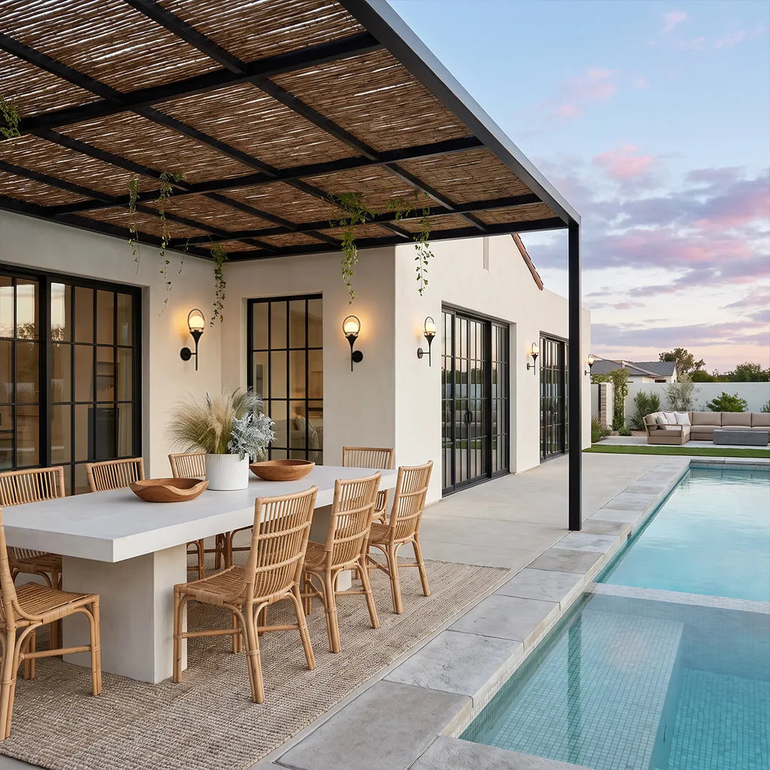 Wall mounted outdoor lighting illuminating a modern poolside dining patio beneath a black pergola.
