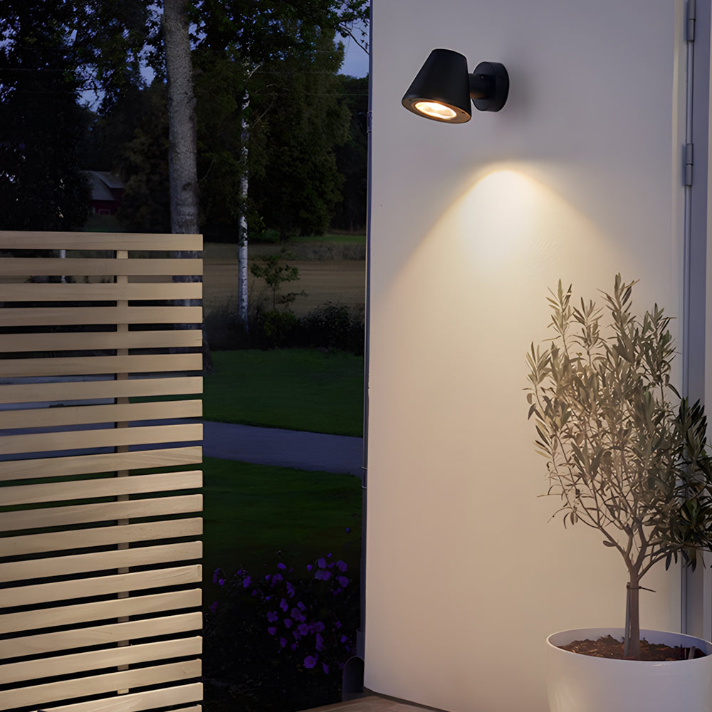 Compact wall-mounted spotlight highlighting garden features with focused beam on wooden fence