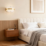 Wall sconce glass creating warm illumination above mid-century modern nightstand in neutral-toned bedroom with upholstered headboard