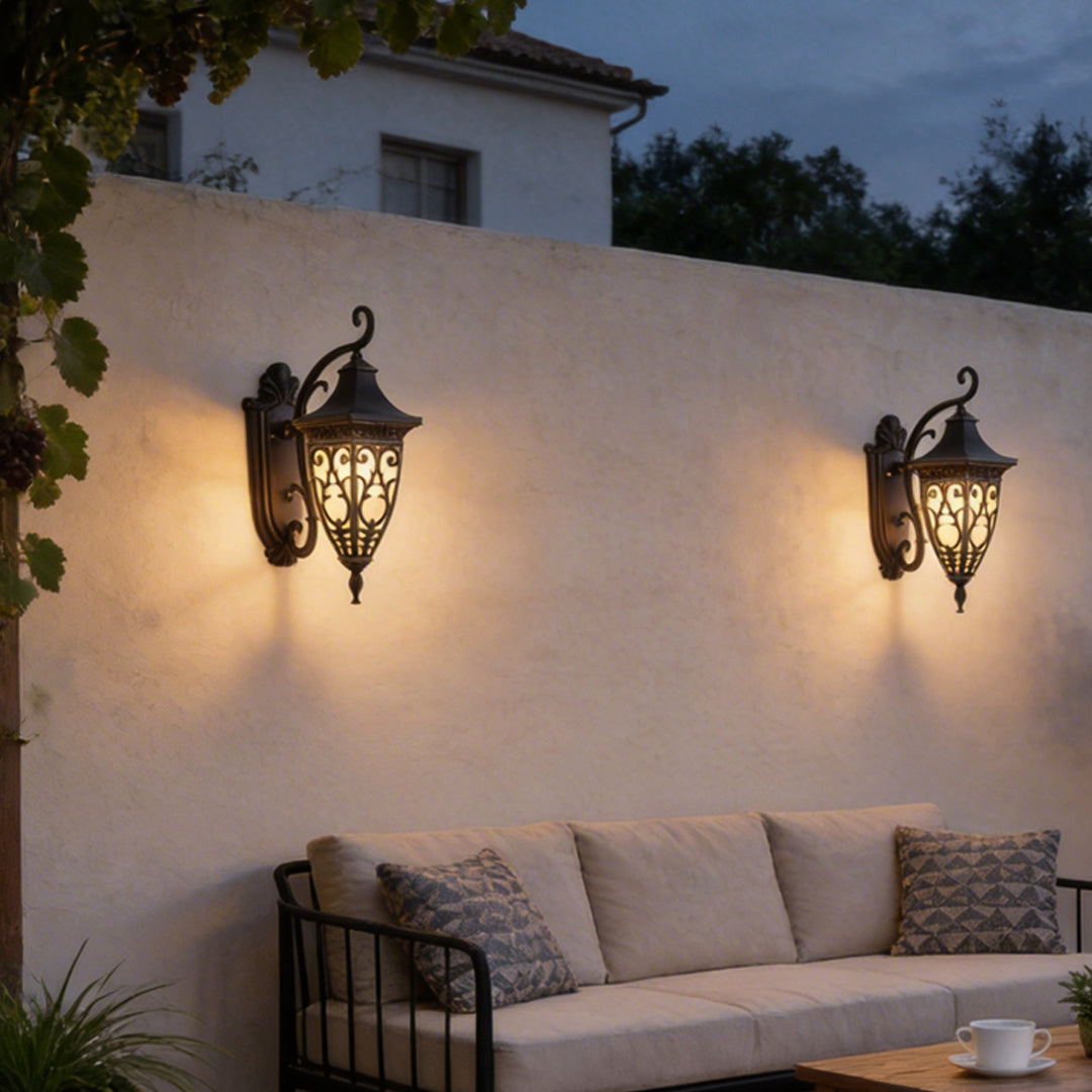 Wall sconce lantern with intricate metalwork, installed on an exterior wall near a patio.