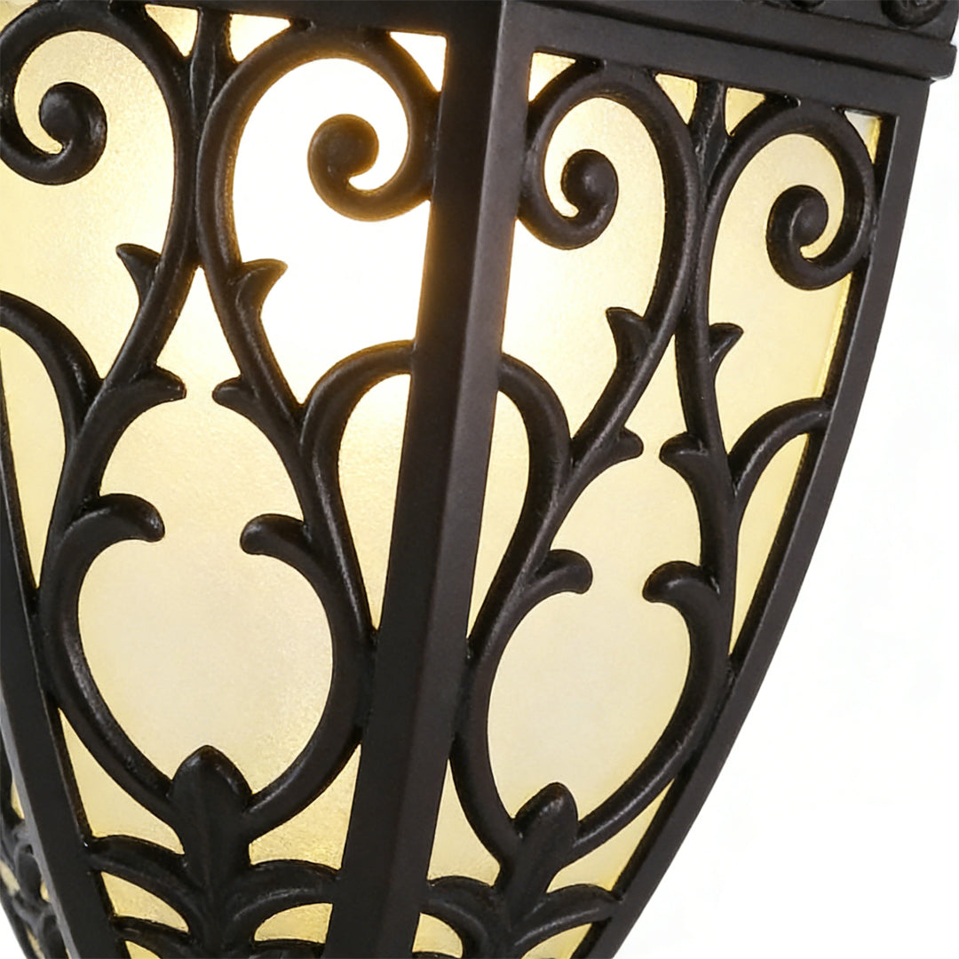 Wall sconce lantern with a close-up of its intricate metalwork and glass panels.