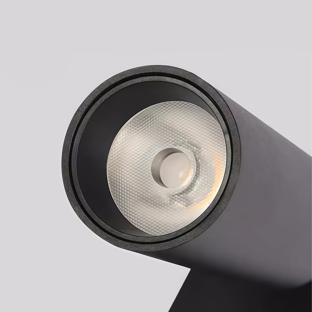 Close-up detail of black wall sconce reading light with cylindrical spotlight and textured metal finish.