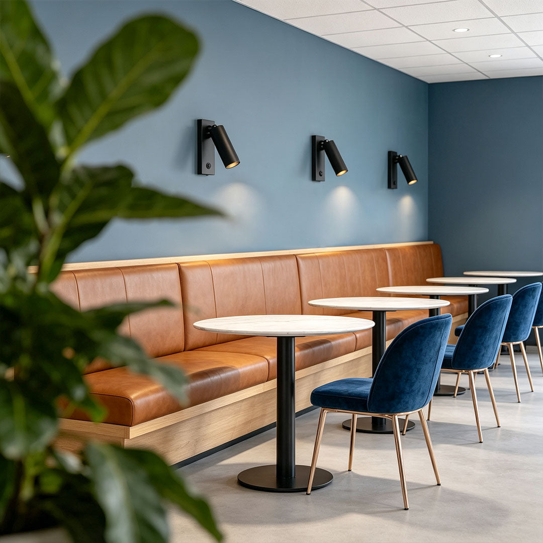 Contemporary wall sconce reading light illuminating cafe seating area with adjustable black spotlight fixtures.