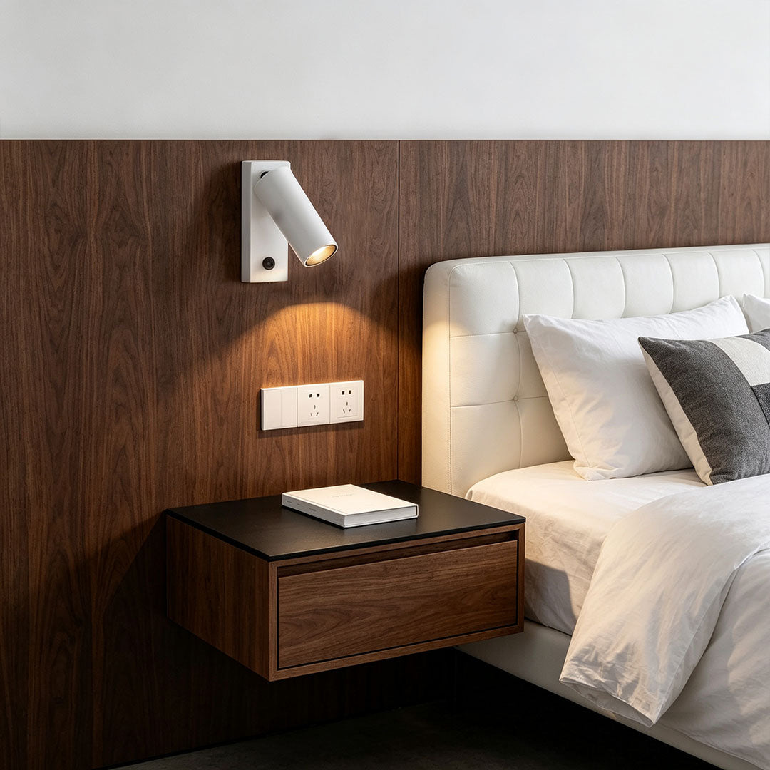 Modern wall sconce reading light installed beside bed with warm focused lighting and wood panel backdrop.