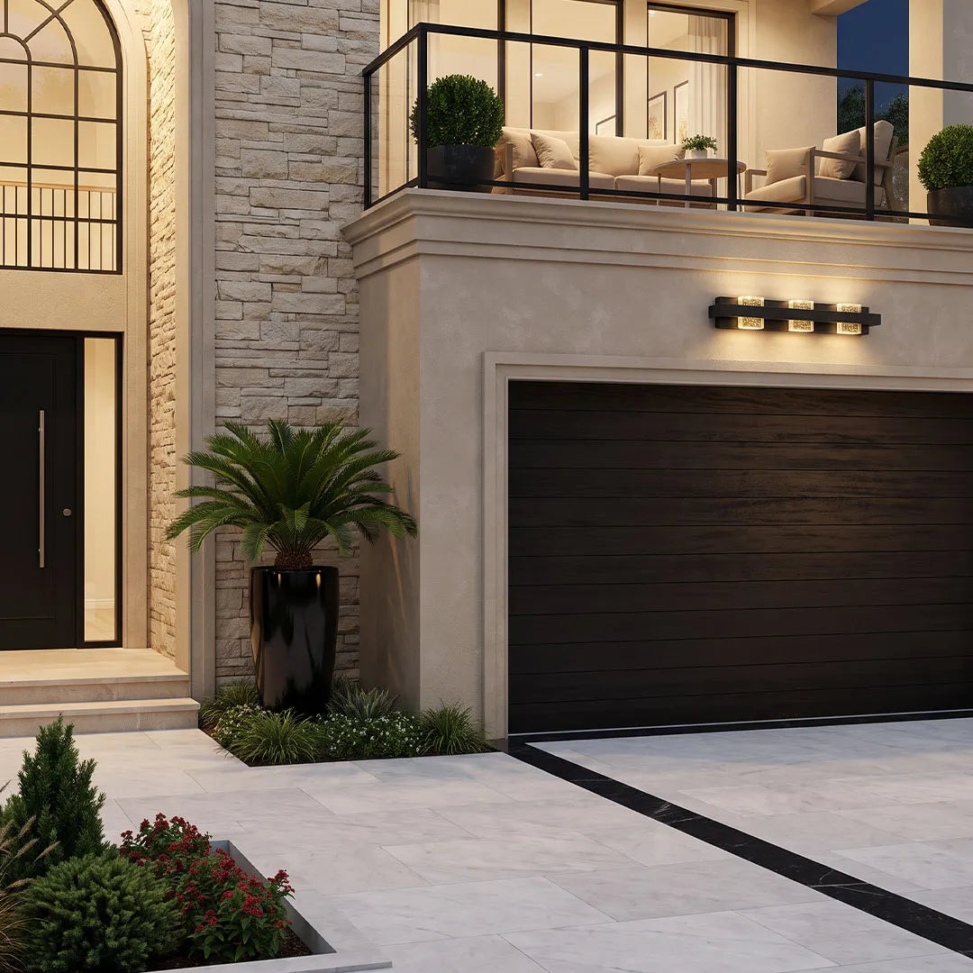 Wall sconce up and down light mounted horizontally above a modern garage door on a stone facade.