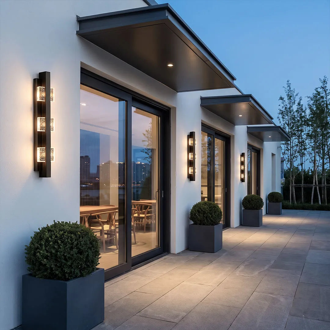 Wall sconce up and down light arranged on a contemporary home exterior near large glass doors.