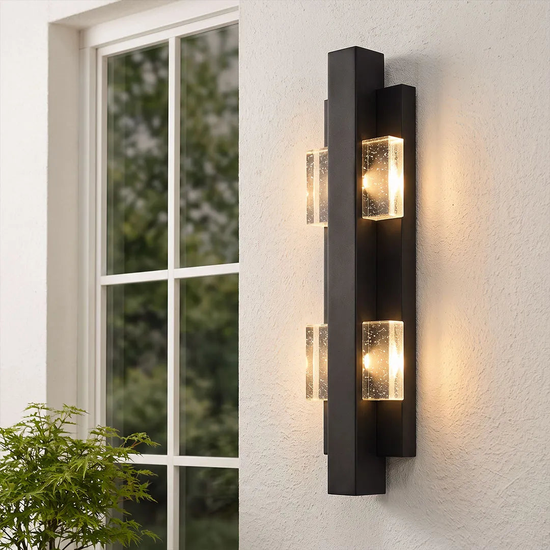 Wall sconce up and down light mounted vertically beside a window on a modern exterior wall.