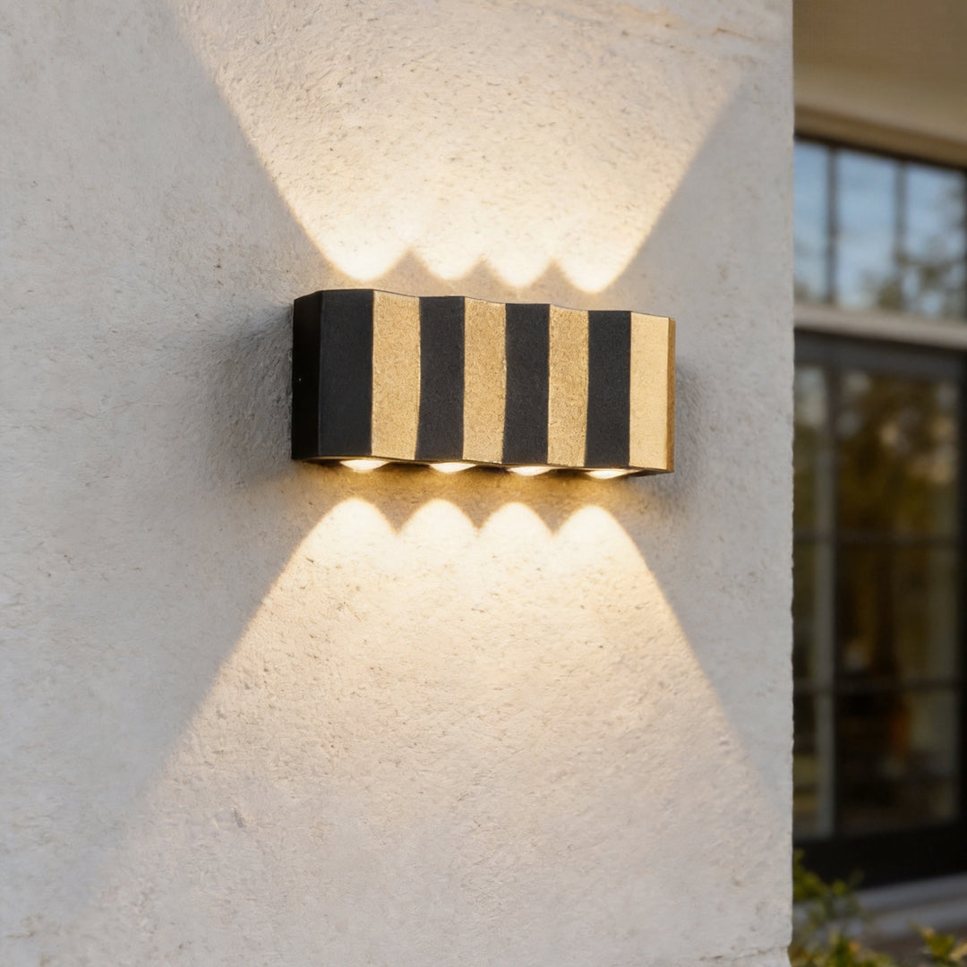Wall sconce up-down light mounted on an exterior wall, casting warm beams above and below.