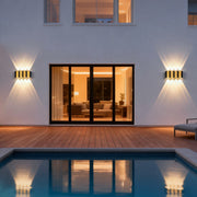 Wall sconce up-down light illuminating a modern house exterior with warm directional glow.