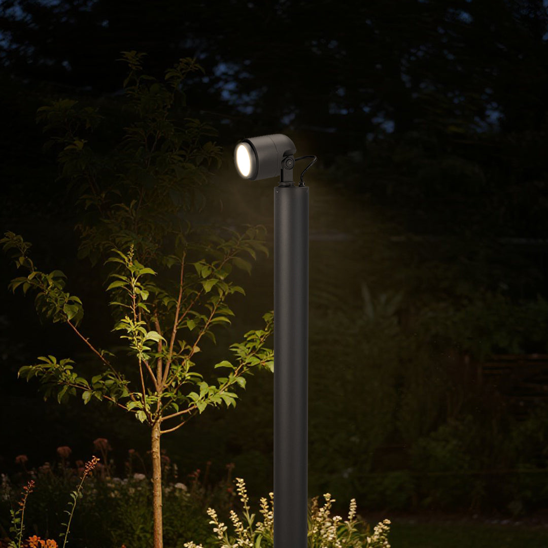 Warm white bollard light creating ambient illumination along outdoor pathway with trees and landscaping