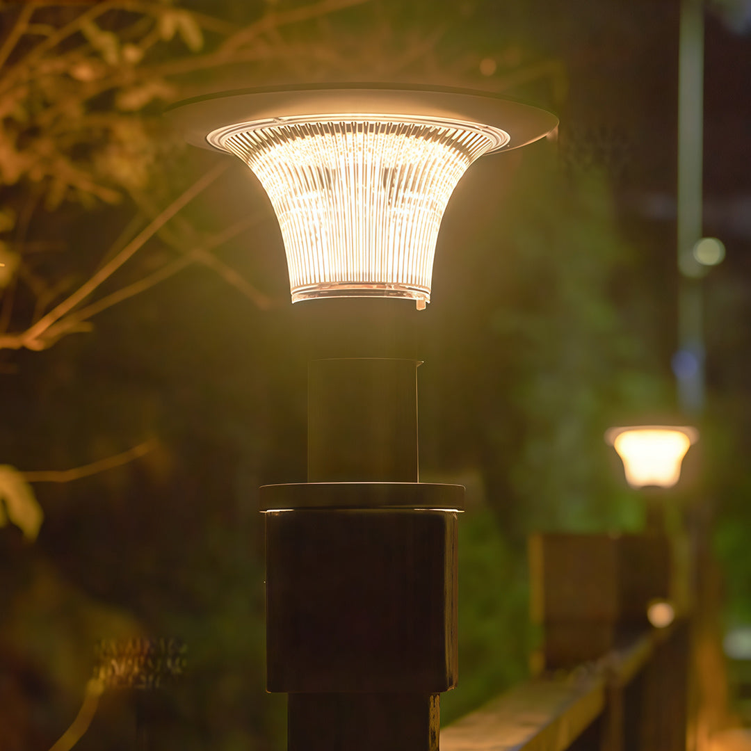 Warm, bright illumination from a fence post cap light on a dark post in a garden at night.