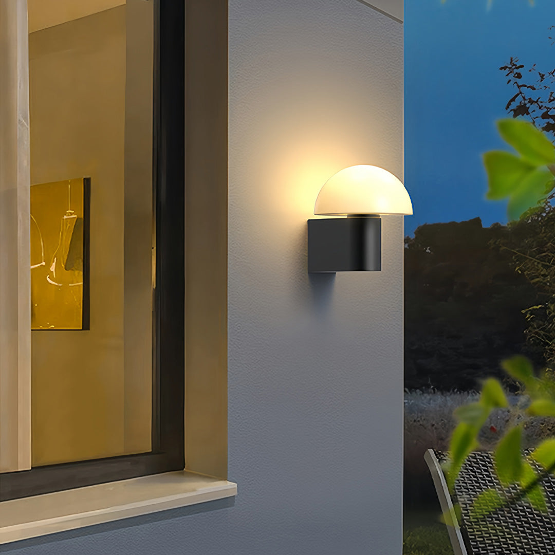 Warm glowing outdoor wall light sconce mounted beside a modern entrance, creating a soft welcoming ambiance.