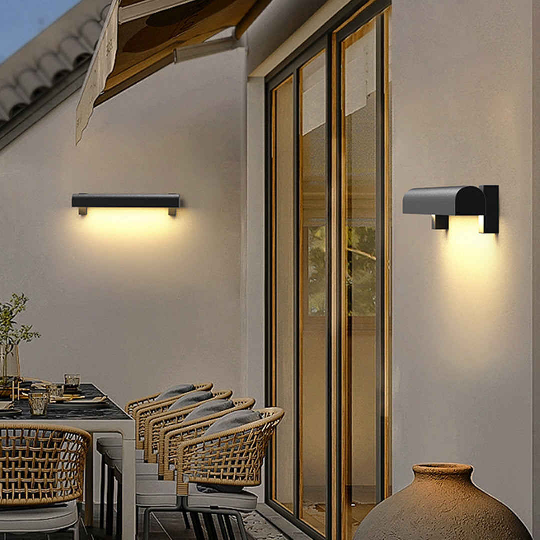 Warm glowing outdoor wall sconce light fixtures installed along a modern exterior walkway at dusk.