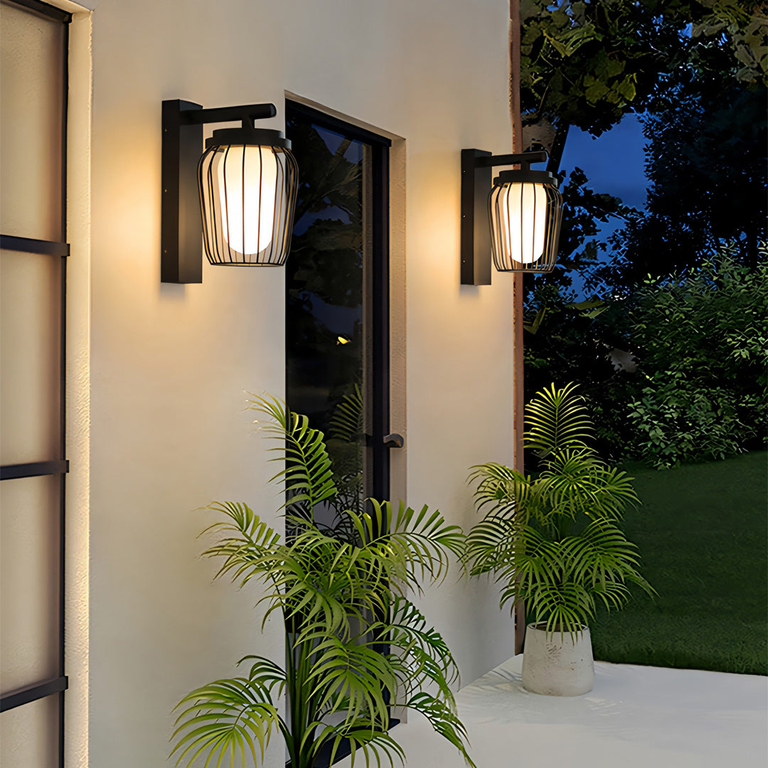 Warm glowing outdoor wall lantern sconce installed on a white exterior wall, creating a welcoming evening atmosphere.