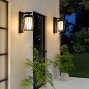Warm glowing outdoor wall lantern sconce installed on a white exterior wall, creating a welcoming evening atmosphere.