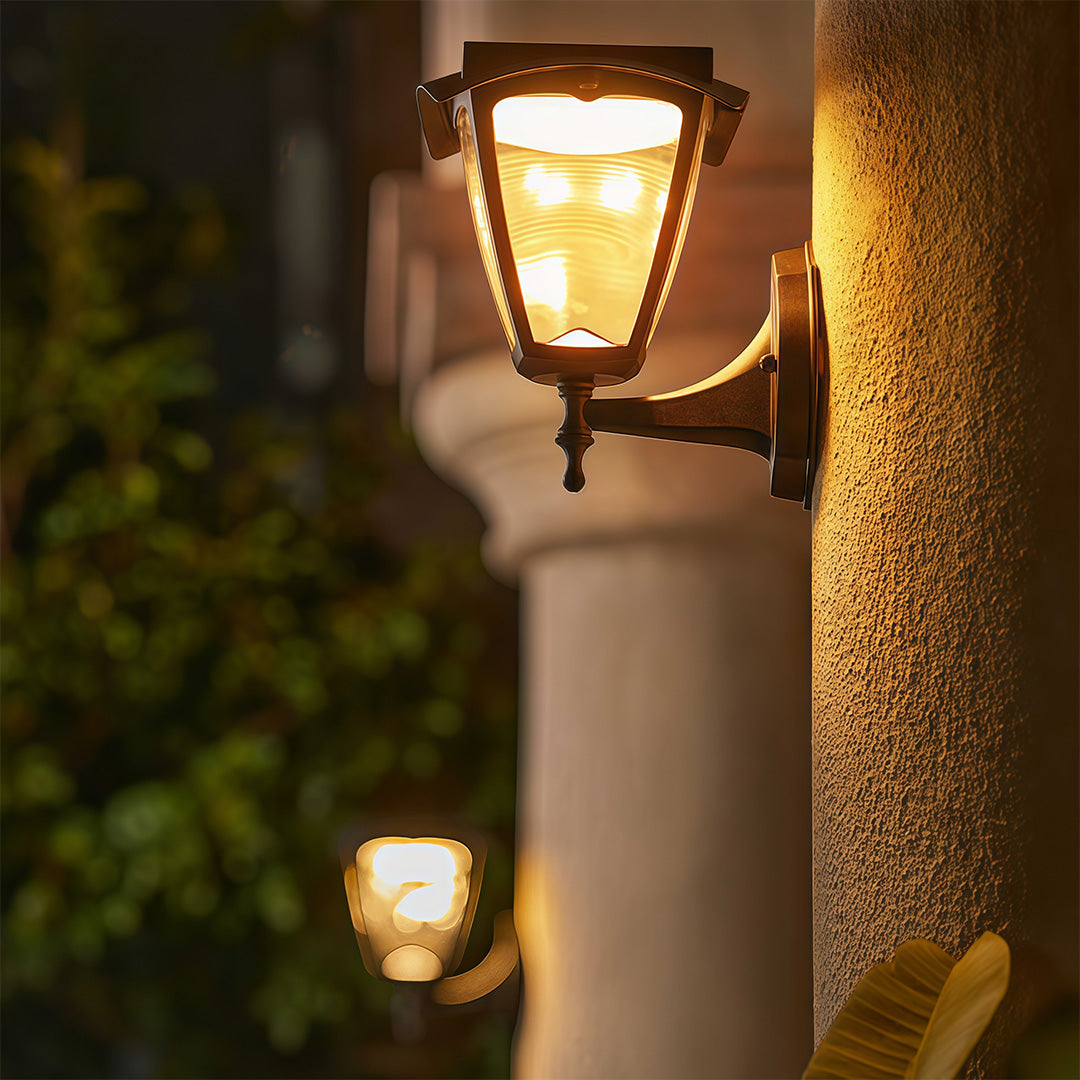 Warm glowing outdoor wall lighting black sconces providing ambient light on classical pillars.