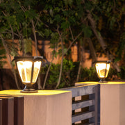 Warm-glowing solar light pillar fixtures in a classic lantern style, illuminating a modern fence at night.