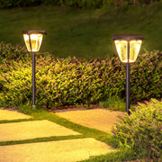 Warm-glowing solar powered path lighting fixtures in a classic lantern style, lining a stone walkway.