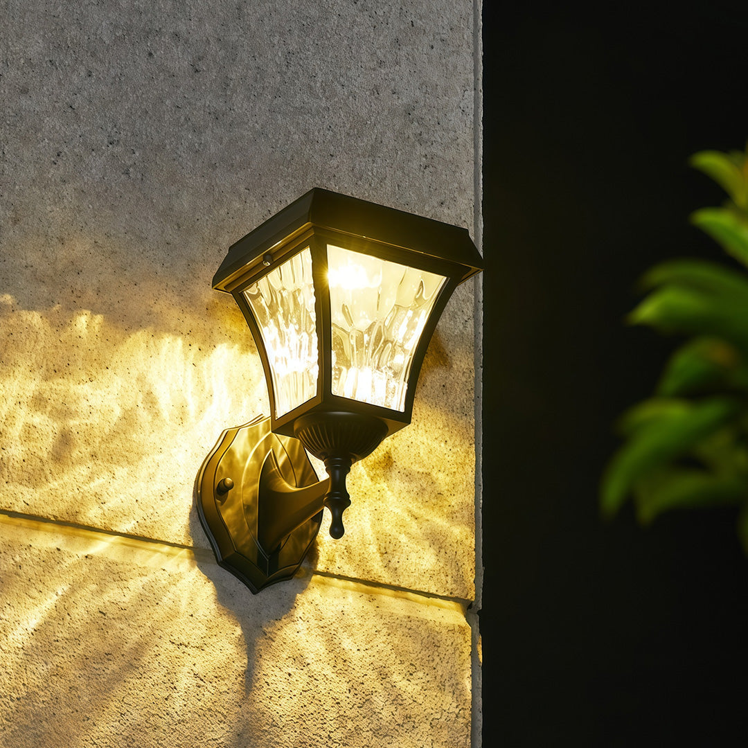 Warm illumination from wall-mounted solar outdoor sconce lights with crackle glass on an exterior stucco wall.