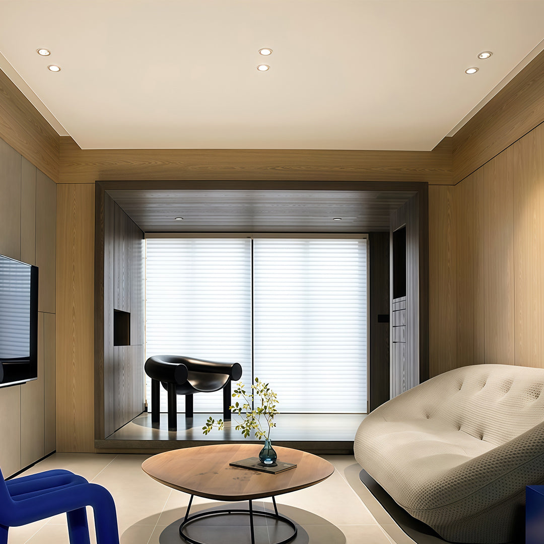 Warm indoor spotlights creating ambient glow in contemporary living room with glass shade chandelier style ceiling fixtures.