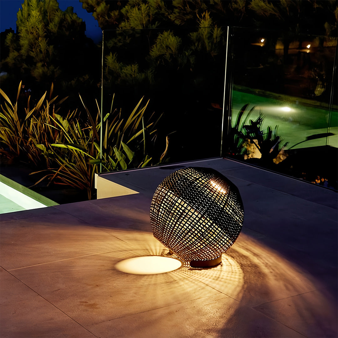 Outdoor globe lantern providing warm, low-level illumination on a modern patio floor, ideal for nighttime ambiance.