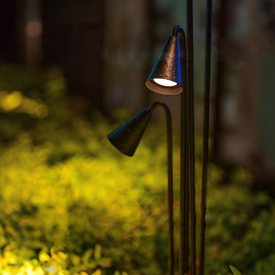 Warm-toned metal landscape lights illuminating golden ornamental grasses in sophisticated residential garden lighting design