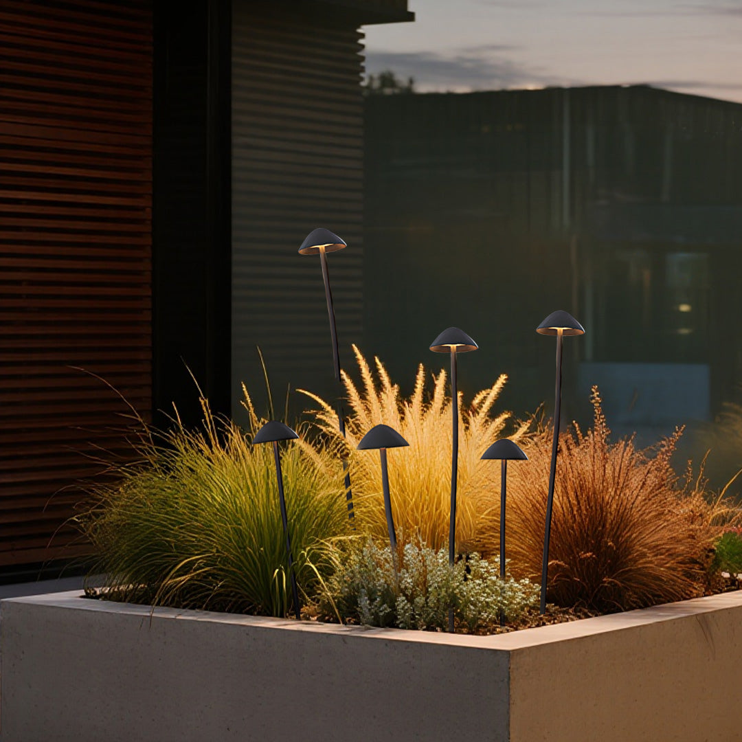 Warm-lit mushroom garden lights highlighting ornamental plants in modern landscape bed design with architectural elements