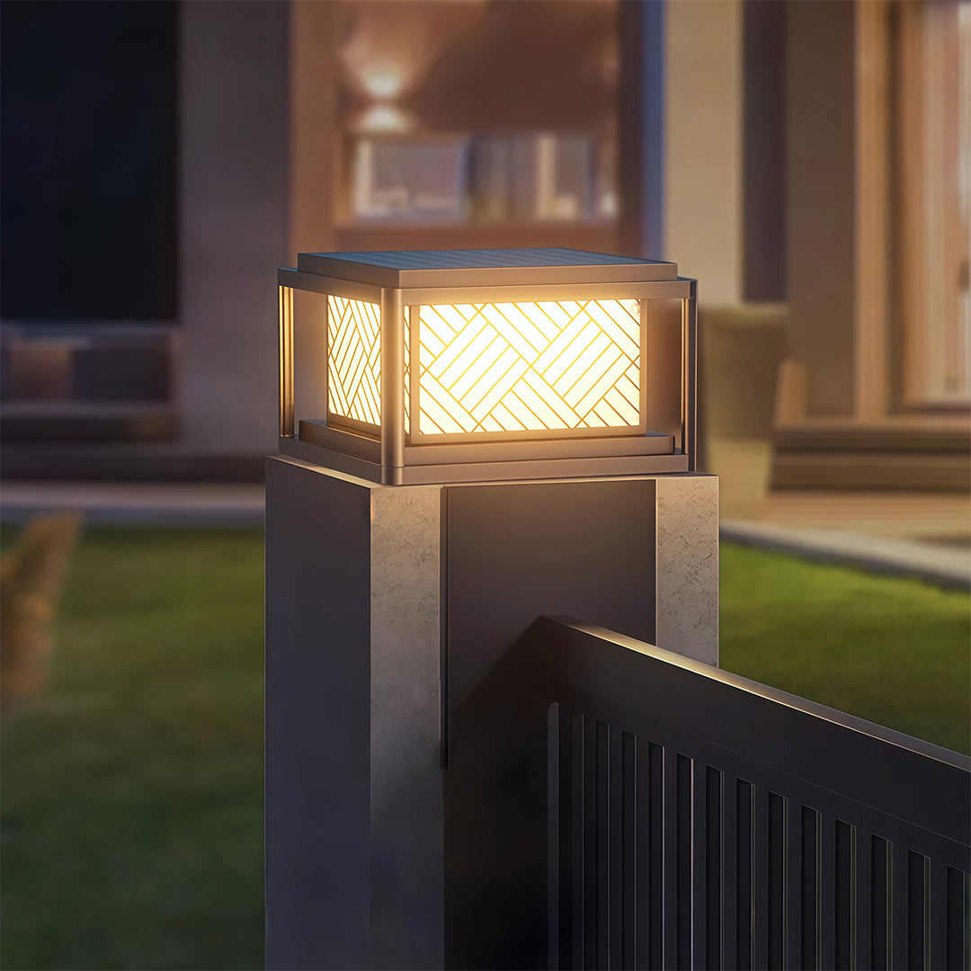 Warm outdoor pillar LED light brightening a front yard walkway and fence area.