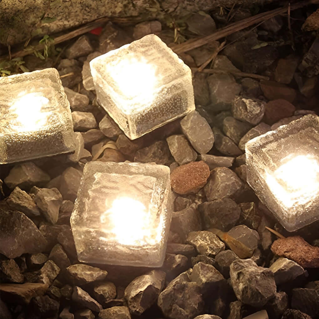 Warm white ice cube outdoor lights resting on decorative gravel stones.