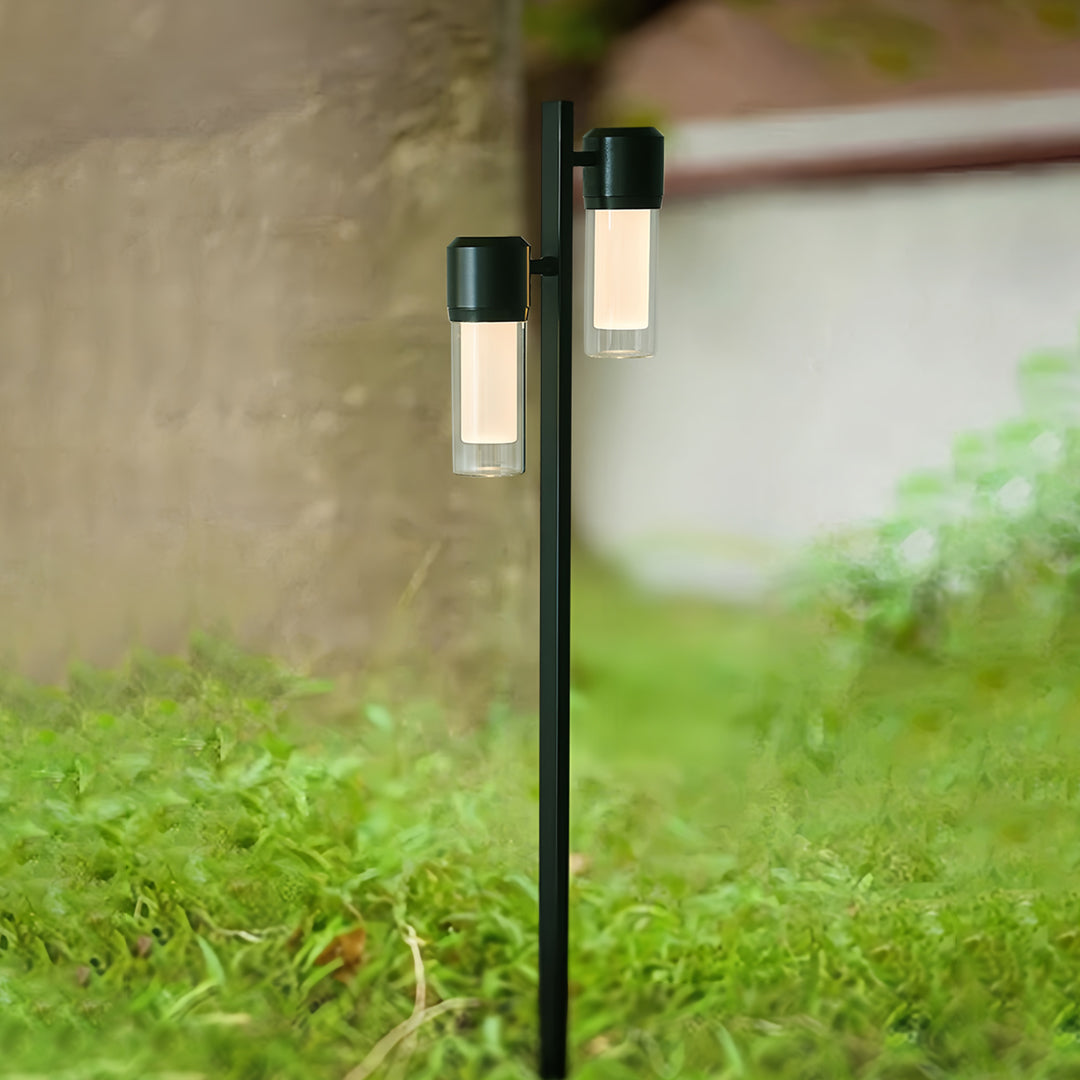 Close-up of a contemporary path light standing beside a wall, casting warm downward illumination.