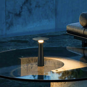 Outdoor led table lamp illuminating water reflections in a night setting.