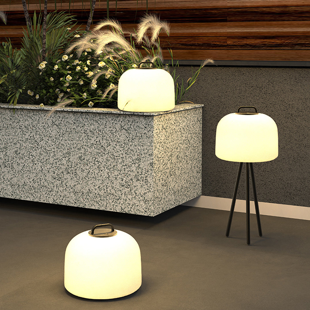 Landscape corner featuring several waterproof outdoor floor lamps glowing warmly among stones and plants.