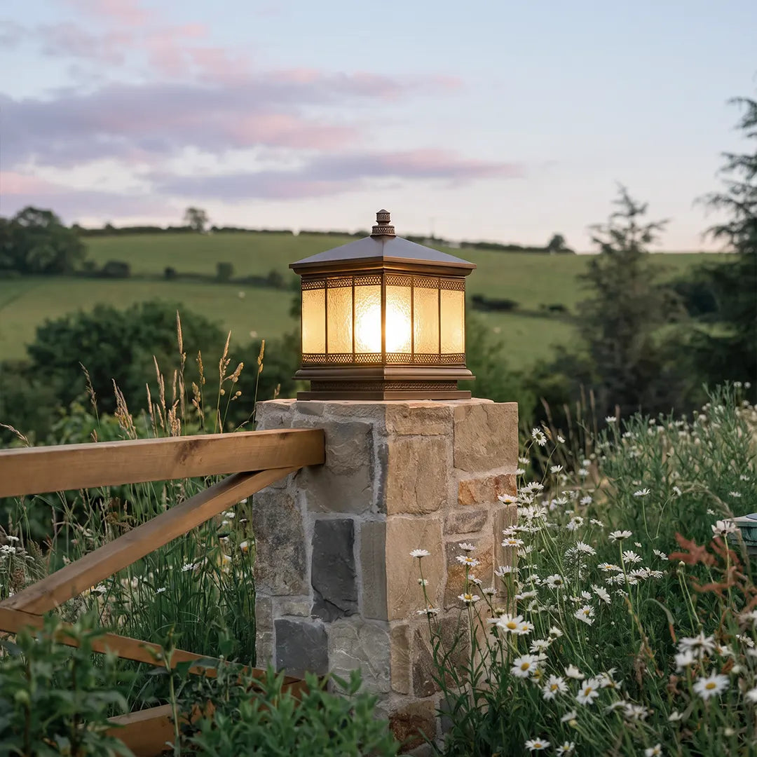 Waterproof outdoor gate pillar light set on a stone entrance post along a rustic countryside fence.