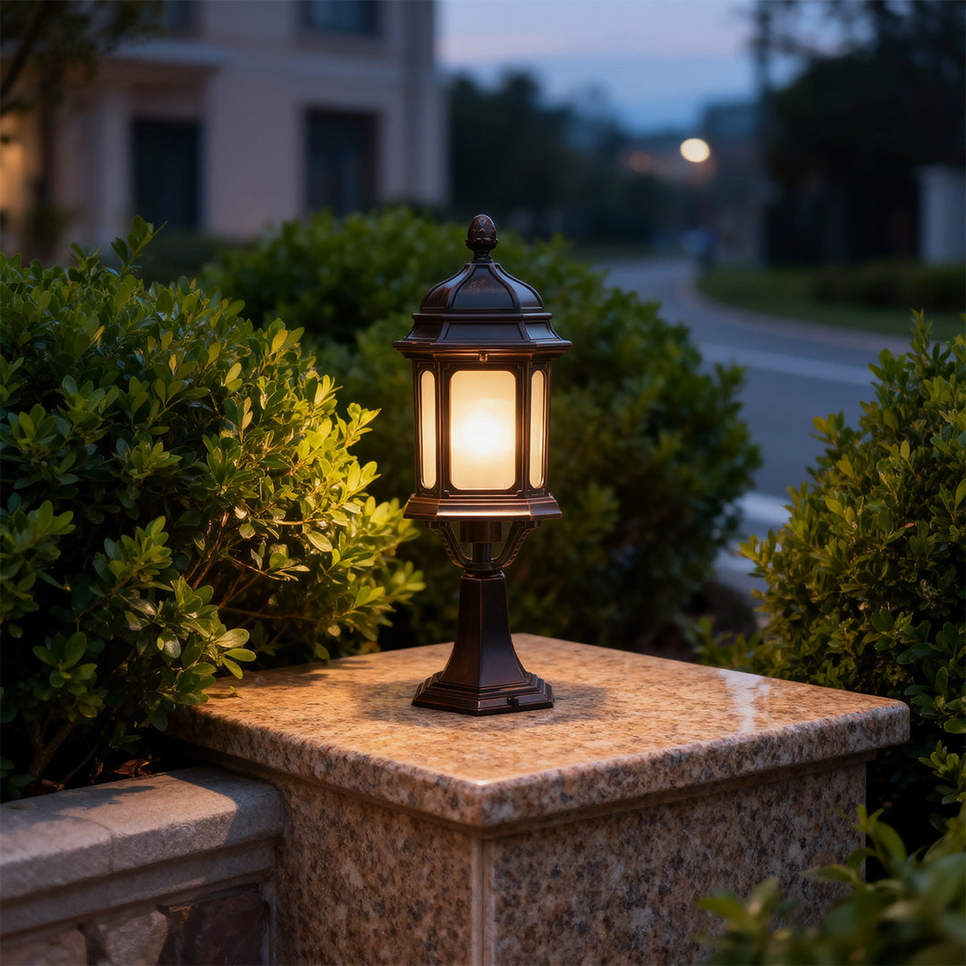 Single waterproof outdoor pendant light glowing warmly on decorative stone pier in evening garden setting