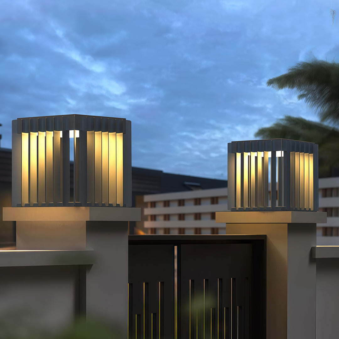 A nighttime outdoor view featuring waterproof outdoor pillar lights illuminating a terrace with soft warm lighting.